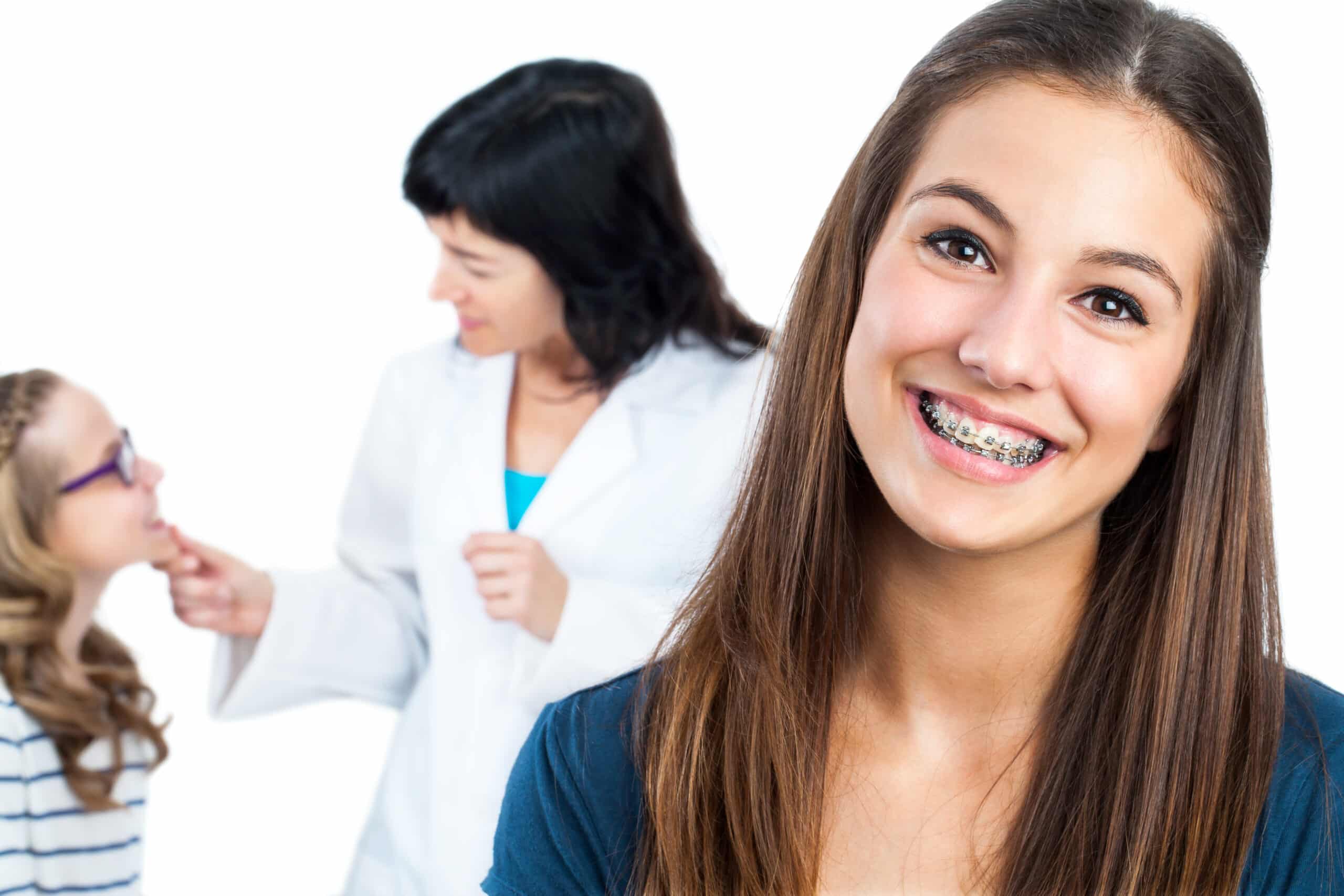 Young woman smiling with metal braces in an orthodontist office