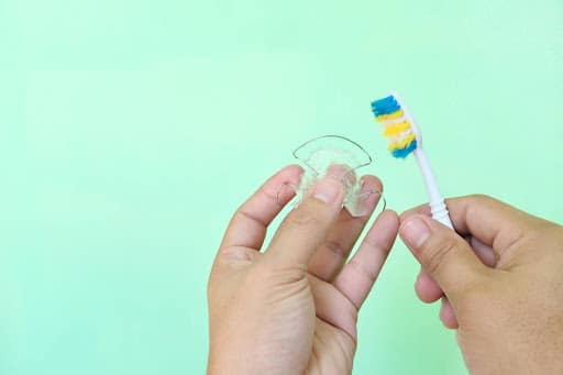 Properly brushing a clear retainer to remove plaque and maintain retainer hygiene