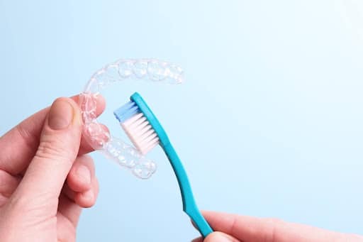 Cleaning a clear orthodontic retainer using a soft toothbrush and gentle technique