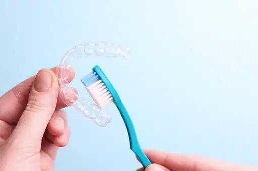 Cleaning a clear orthodontic retainer using a soft toothbrush and gentle technique
