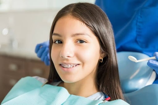Teen girl smiling while getting braces adjusted at orthodontist office