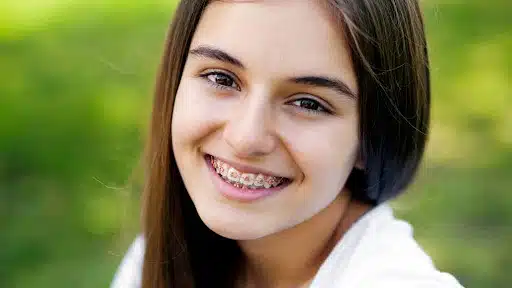 Teenage girl smiling outdoors with metal braces